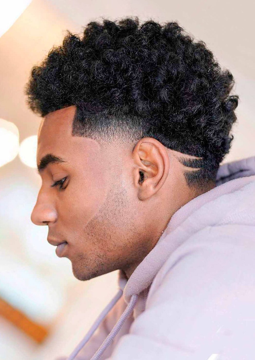 Low Fade with Thick Curly Top and Geometric Design