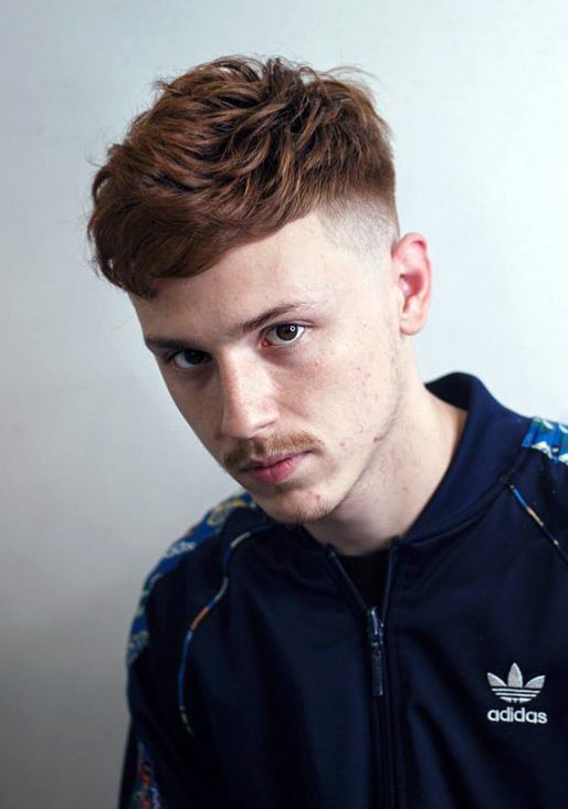 Portrait of young man with red hair against orange background stock photo